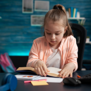 Meisje leest een boek aan haar bureau.