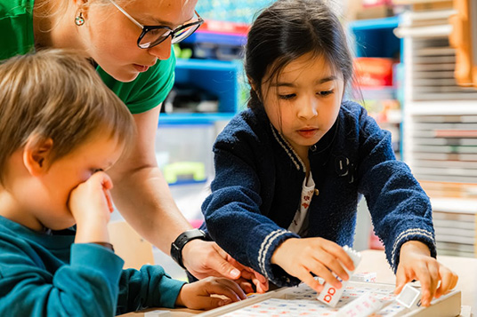 Kleuterleerkracht met kleuters aan het werken aan een taak